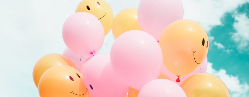 Dzelteni un rozā baloni ar uzzīmētām smaidīgām sejām.