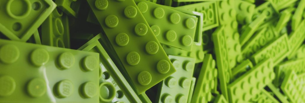 Daudz zaļiem vienāda izmēra LEGO klucīši samesti viens otram virsū kaudzē.