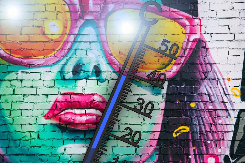 Graffiti zīmējums uz ķieģeļu sienas - sievietes seja. Viņa ir lielās saulesbrillēs. Šo seju daļēji klāj barometra stabiņš. Tas rāda, ka gaisa temperatūra uzsilusi līdz 39 grādiem pēc Celsija.